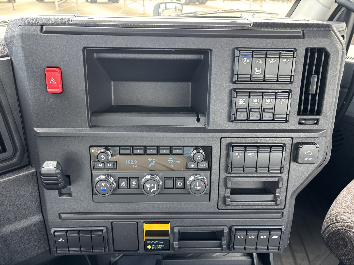 Dashboard of a 2027 Mack AN64 dump truck showing climate controls, hazard button, storage pocket, and various switches.