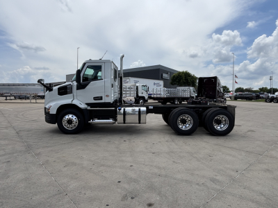 Side view of a white Mack AN64 dump truck chassis with long wheelbase and dual rear axles. No obvious text on vehicle exterior visible.