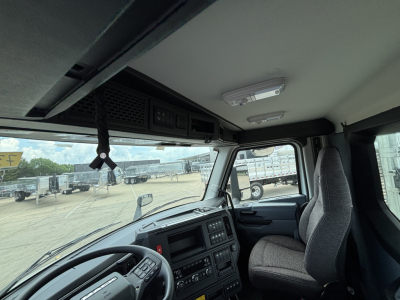 Cab interior of a 2027 Mack AN64 dump truck showing steering wheel, dashboard, and driver seat with overhead dash controls.