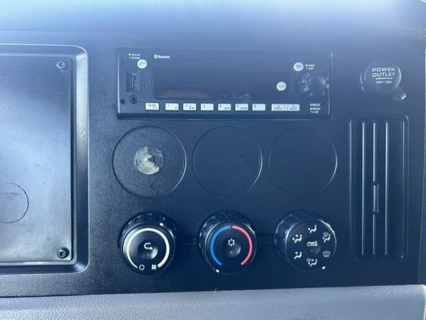Dashboard of a 2022 Freightliner Cascadia 126 showing the radio unit, ventilation controls, and power outlet.