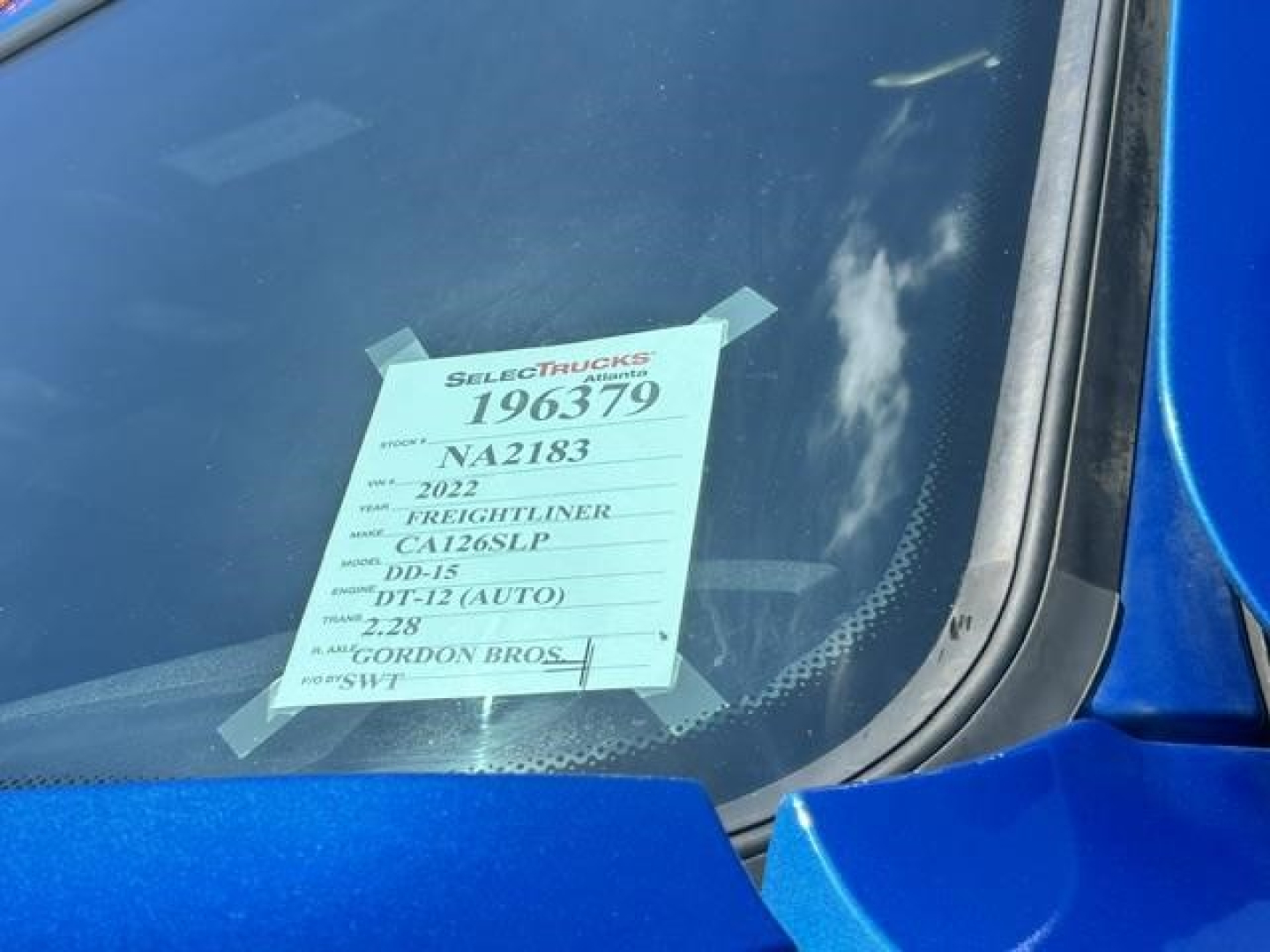 Truck windshield with a yellow inventory tag reading 196379 and 2022 Freightliner Cascadia information visible.