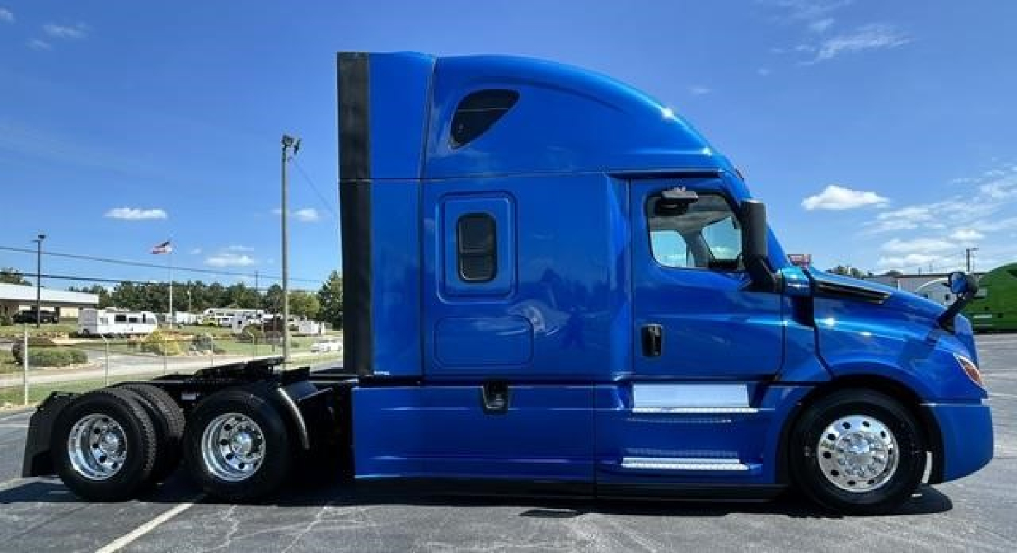 Blue Freightliner Cascadia 126 sleeper cab tractor side view showing chrome wheels and dual rear axles.