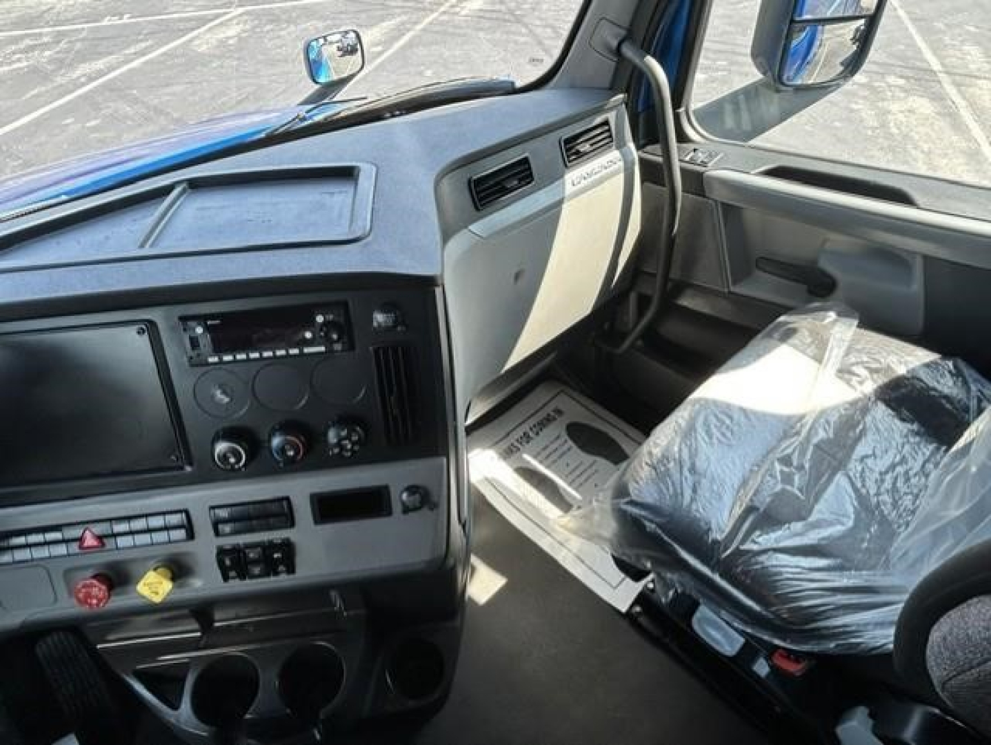 Cab interior of a Freightliner Cascadia sleeper showing dashboard controls and cabin area.