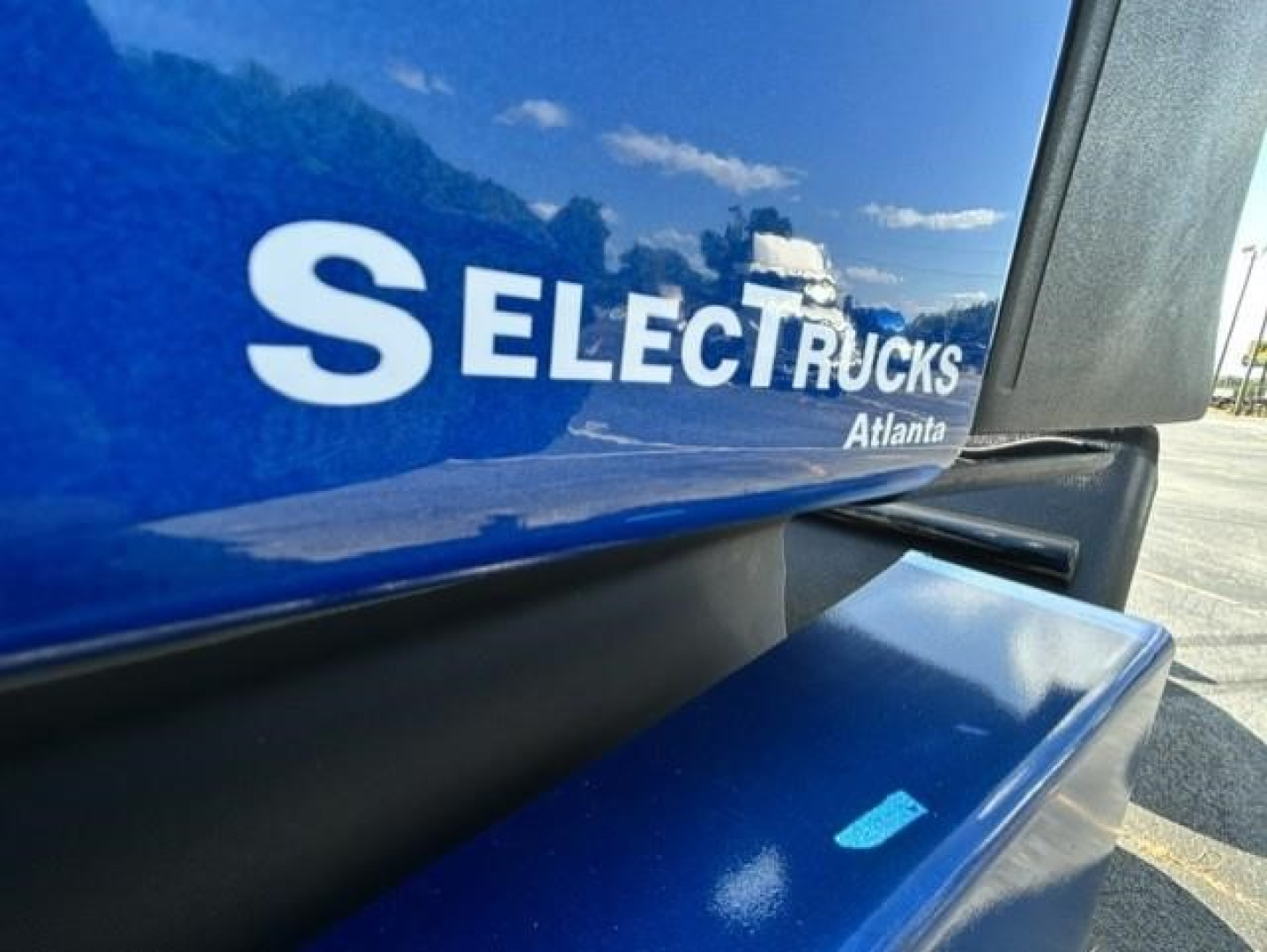 Truck body side showing blue Freightliner Cascadia with Select Trucks Atlanta logo and partial model text.