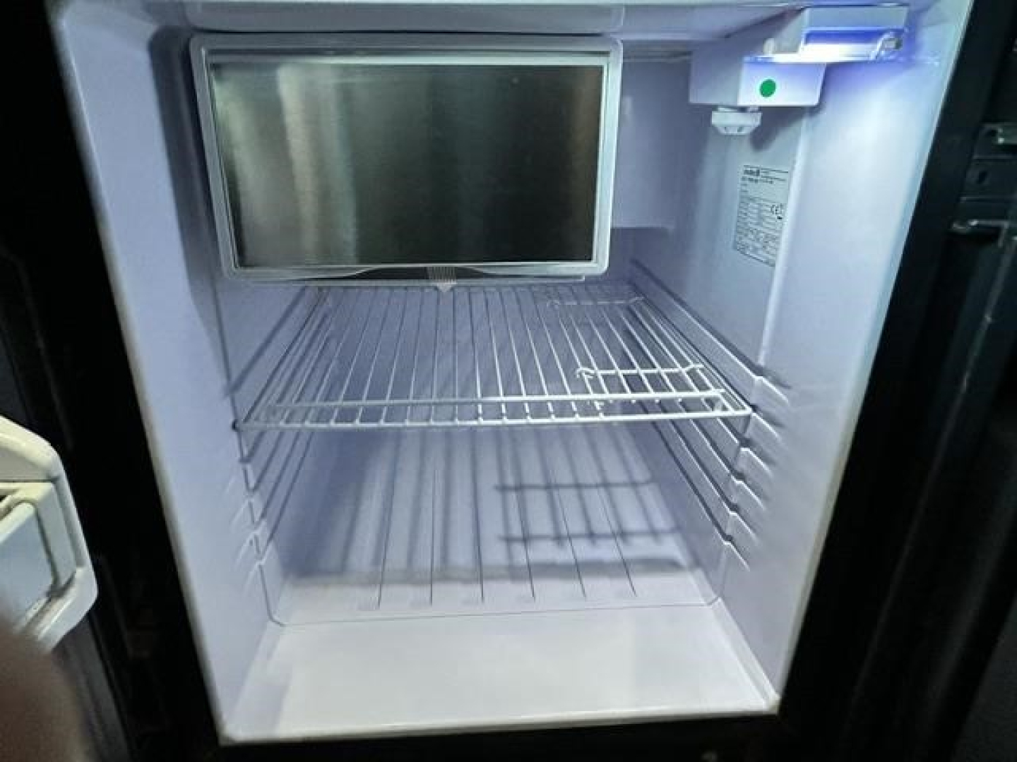 Freightliner Cascadia truck sleeper fridge interior view with empty fridge space and small freezer area.