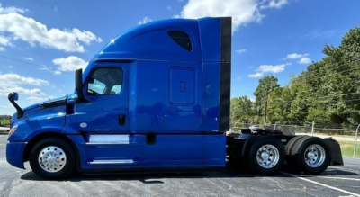 Truck side view of a blue 2022 Freightliner Cascadia 126 conventional sleeper with a high aerodynamic cab and dual rear axles.