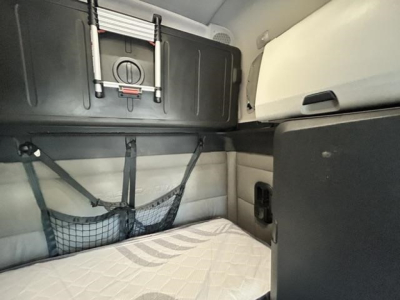 Freightliner Cascadia 126 sleeper cab interior showing storage shelf, netting, and overhead cabinet.