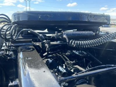 View of a Freightliner Cascadia engine bay showing air lines, hoses, and electrical cables around the engine cover.