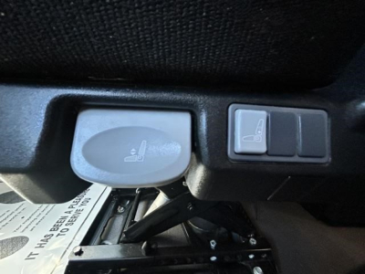 Seat adjustment lever and control switches in a Freightliner Cascadia cab showing seat adjustment knob and window/mirror control panel.