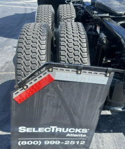 Truck chassis with dual rear axles and mudflap showing SelectTrucks Atlanta contact number.