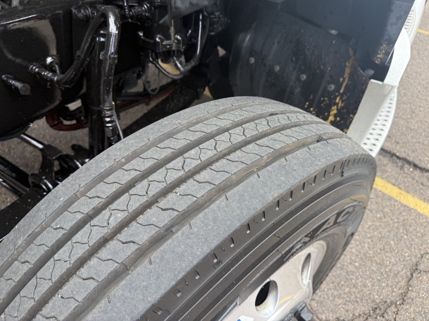 Kenworth T680 front wheel and tire view showing front fender and engine bay area with hoses and components visible