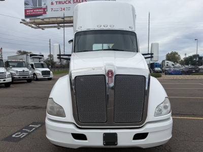 Kenworth T680 front view showing large grille, white cab, side mirrors, and bumper. VIN and stock number visible in listing; equipment appears in a dealership lot.