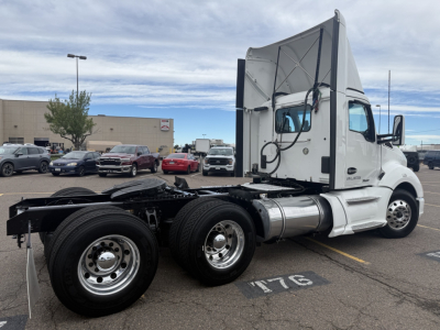 Kenworth T680 tractor with quad rear axles, side view showing cab and fuel tanks.