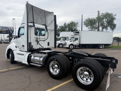 Kenworth T680 tractor from side view with cab raised, showing front wheel, fuel tank, and dual rear axles.