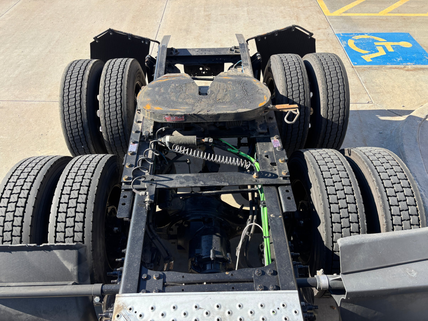 Chassis view of a Freightliner PT126064ST tractor showing dual rear axle setup, frame rails, drivetrain, and suspension components.