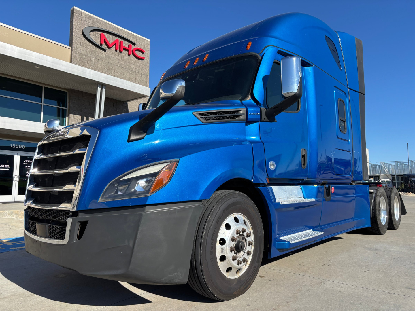 Blue Freightliner PT126064ST tractor-trailer cab showing bold grille and sleeper. Exterior details visible with stock info notations in background.