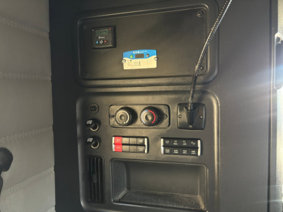 Dashboard panel with control switches and gauges in a Freightliner sleeper cab showing a blue label and various knobs.