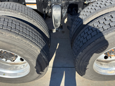 Freightliner truck rear dual-axle area showing dual tires and suspension components, metal frame and undercarriage details.