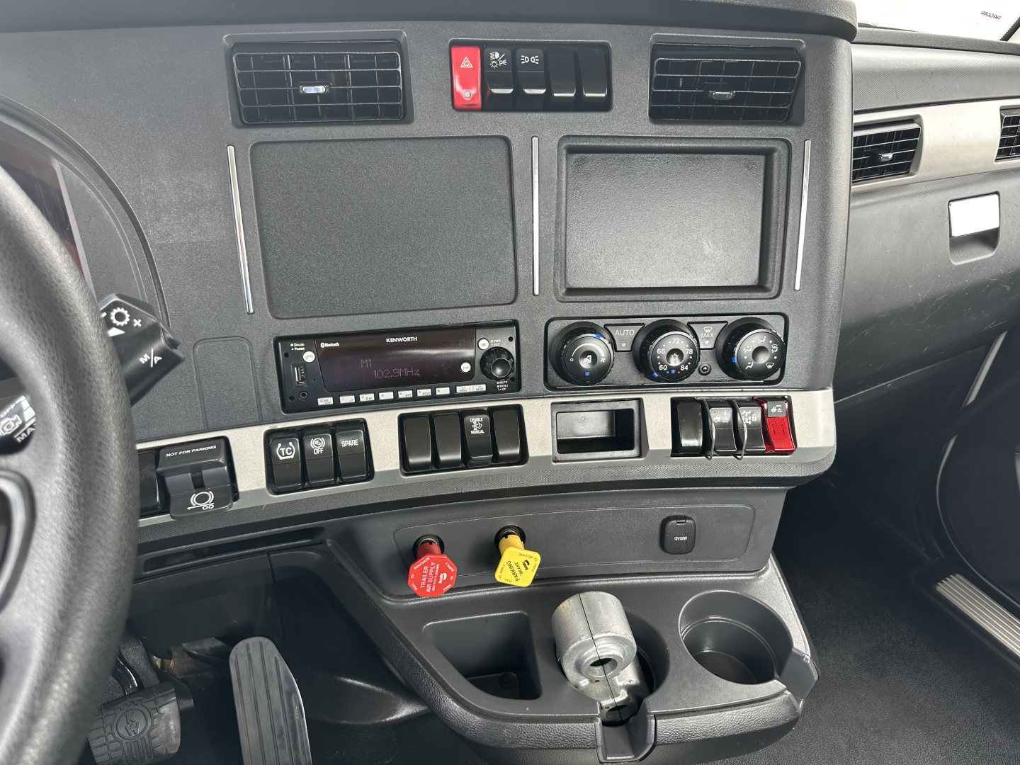 Kenworth T880 dashboard and center console showing control switches, vents, and storage compartments.