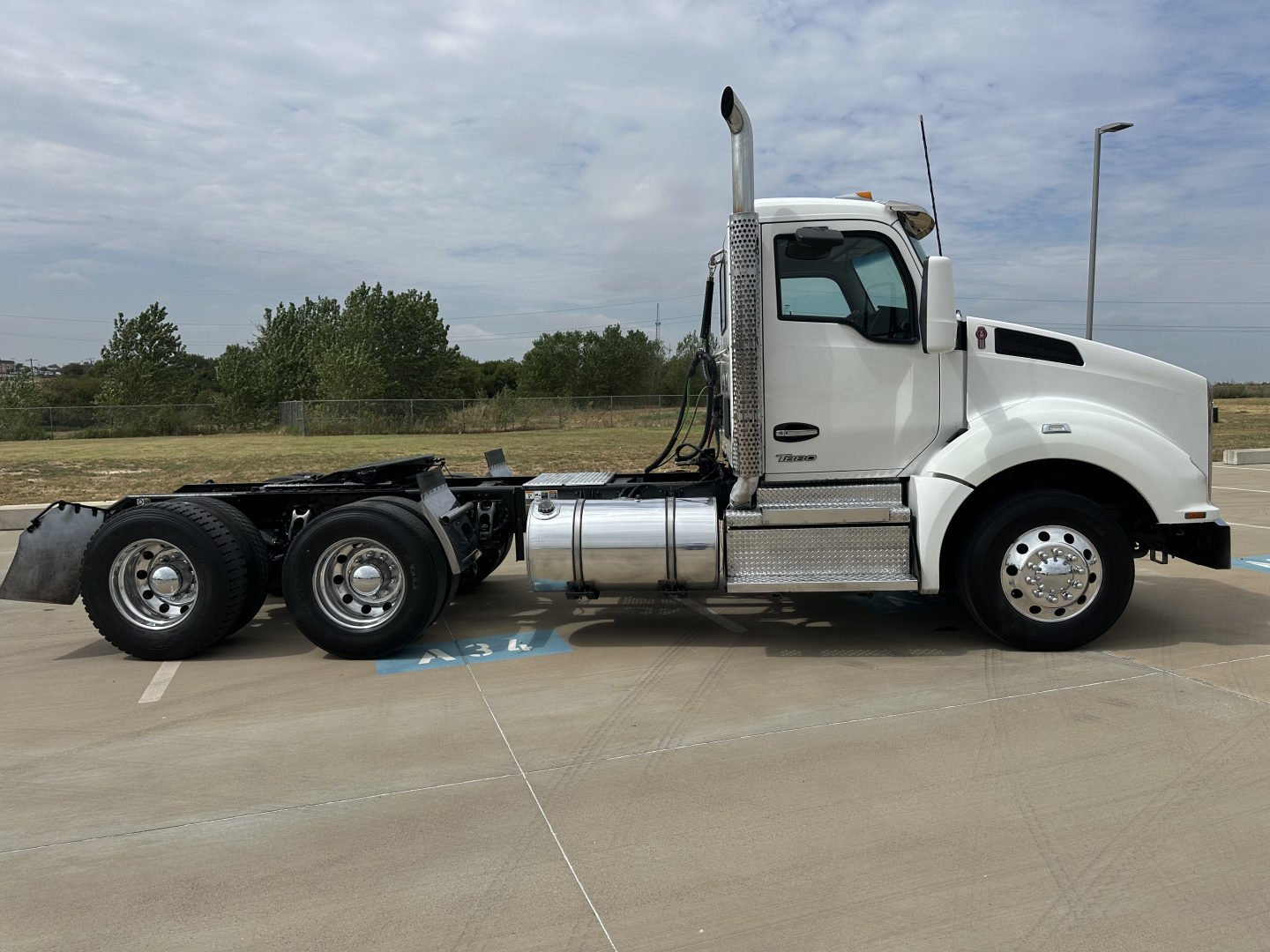 Side view of a white 2022 Kenworth T880 tractor with no trailer, showing the cab, exhaust stack, fuel tanks, and chassis.