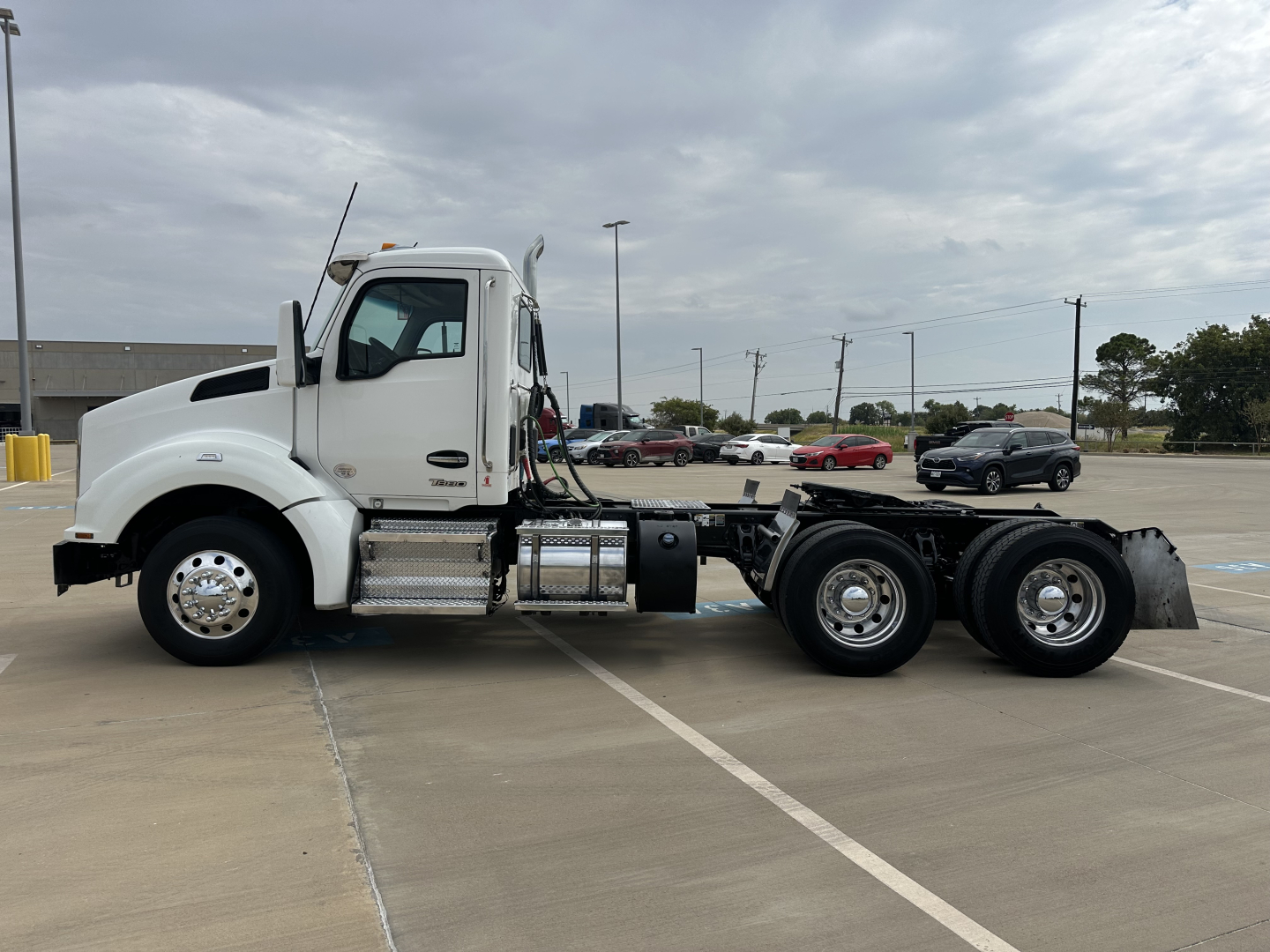 Kenworth T880 conventional daycab tractor in white, side view showing chassis, fuel tanks, and dual rear axles.