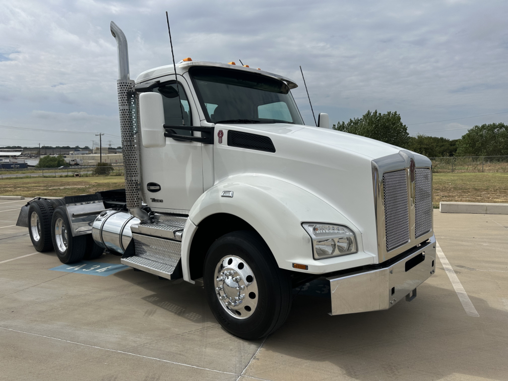 Kenworth T880 conventional daycab truck in white, side view, with chrome grille, fuel tanks, and tall exhaust stacks.