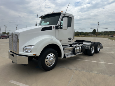 Kenworth T880 conventional daycab tractor in white, side view with dual rear axles, chrome fuel tanks, and large grille