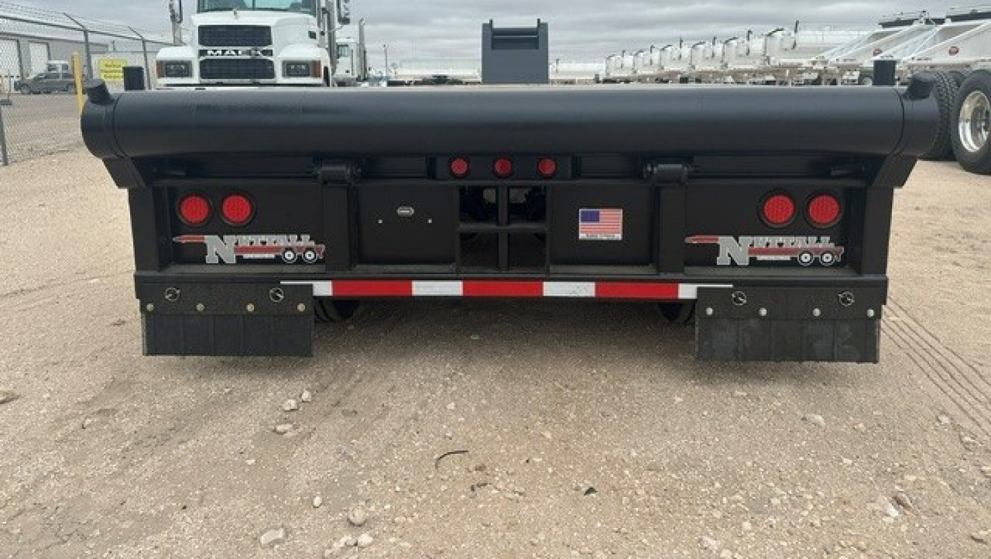 Lowboy trailer rear view showing mud flaps, taillights, reflectors, and bumper with American flag sticker and Nuttall branding.