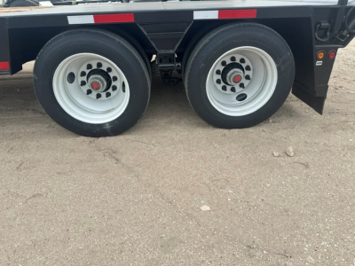 Dual trailer wheels shown on a lowboy trailer with white rims and black fenders.