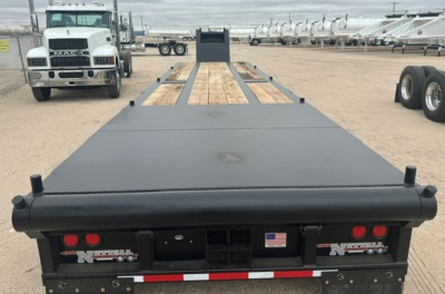 Lowboy trailer deck with wooden center and black steel frame, rear view showing Nuttall logo and US flag plate.