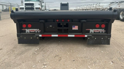 Lowboy trailer rear view showing mud flaps, taillights, reflectors, and bumper with American flag sticker and Nuttall branding.