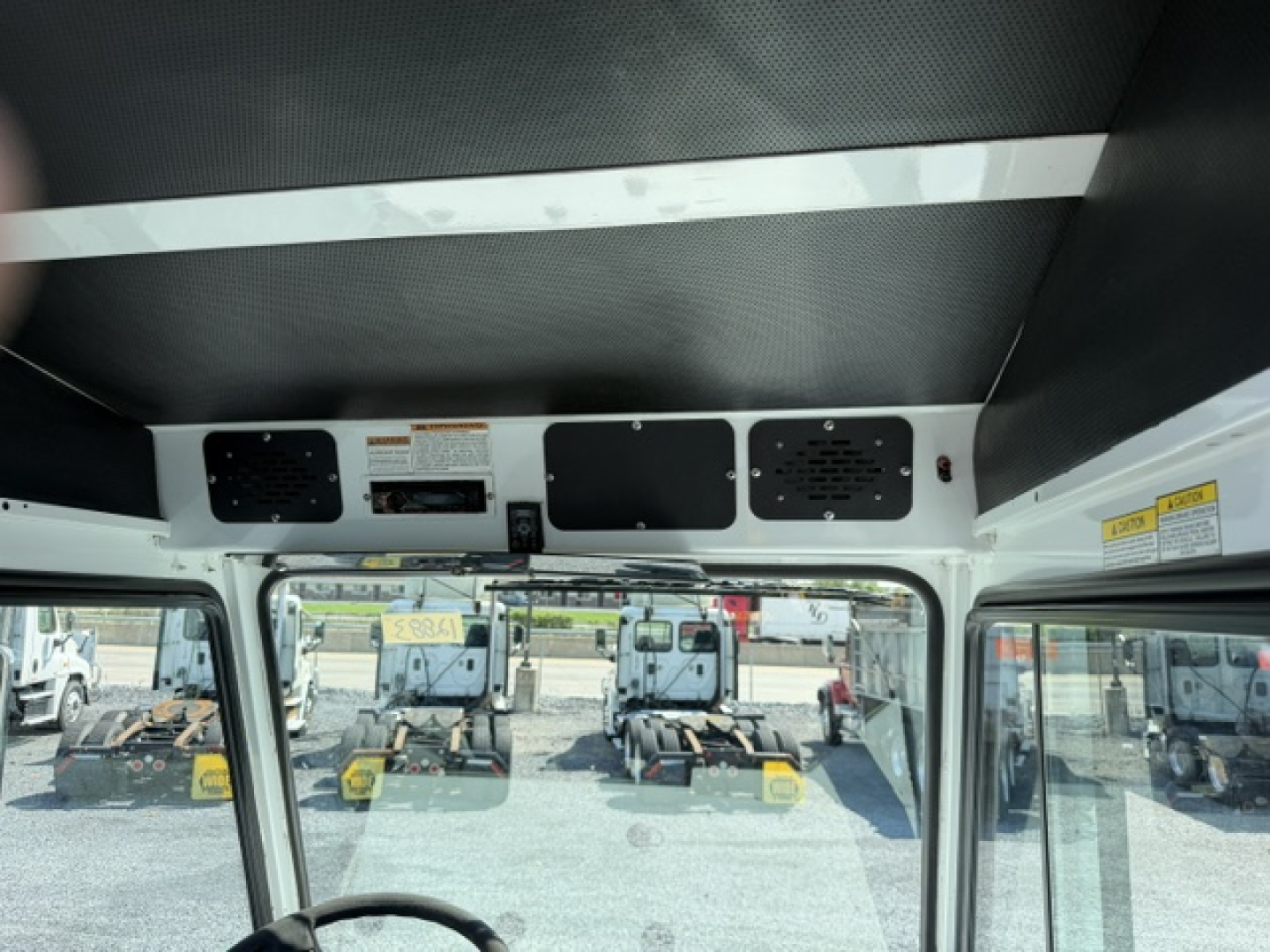 Interior cab view of a 2020 Capacity Sabre DOT truck showing dash area, overhead panels, and driver’s side window with yard equipment visible outside.