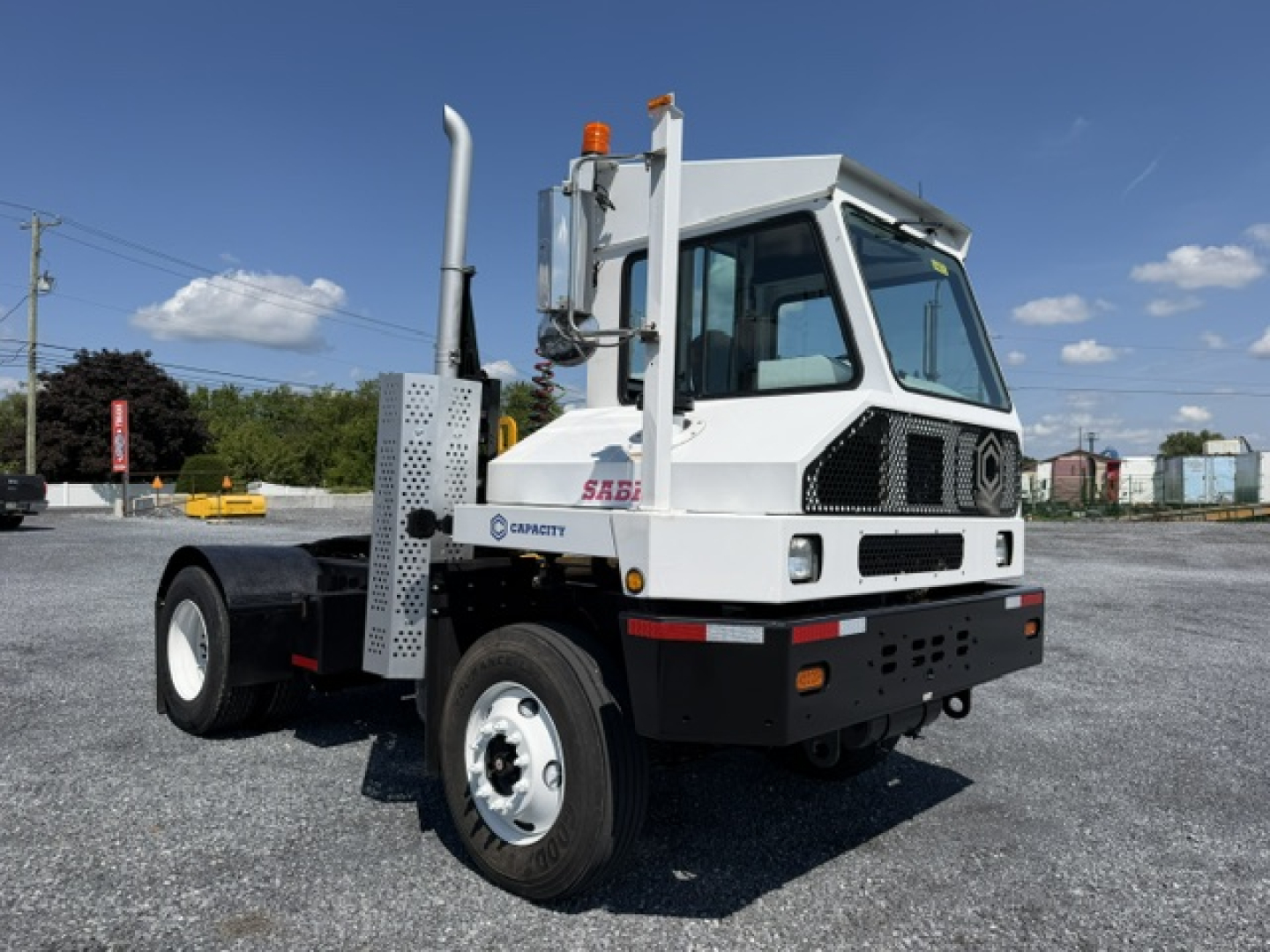 Truck cab side view showing Sabre logo and exhaust stack, front grille, headlights, and off-white body.