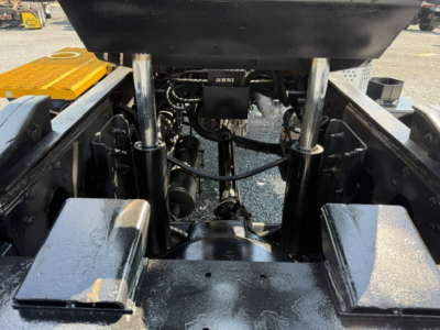 Tractor-trailer truck chassis showing hydraulic cylinders and undercarriage with hoses and components; some labels visible on components.