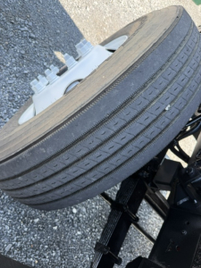 Wheel and tire with hub and part of suspension seen from side showing lug nuts and rim