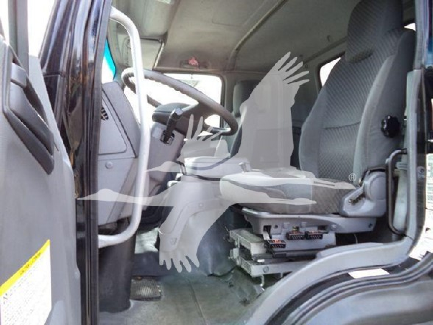 Isuzu truck cab interior showing driver seat and dashboard with pedals and steering wheel.