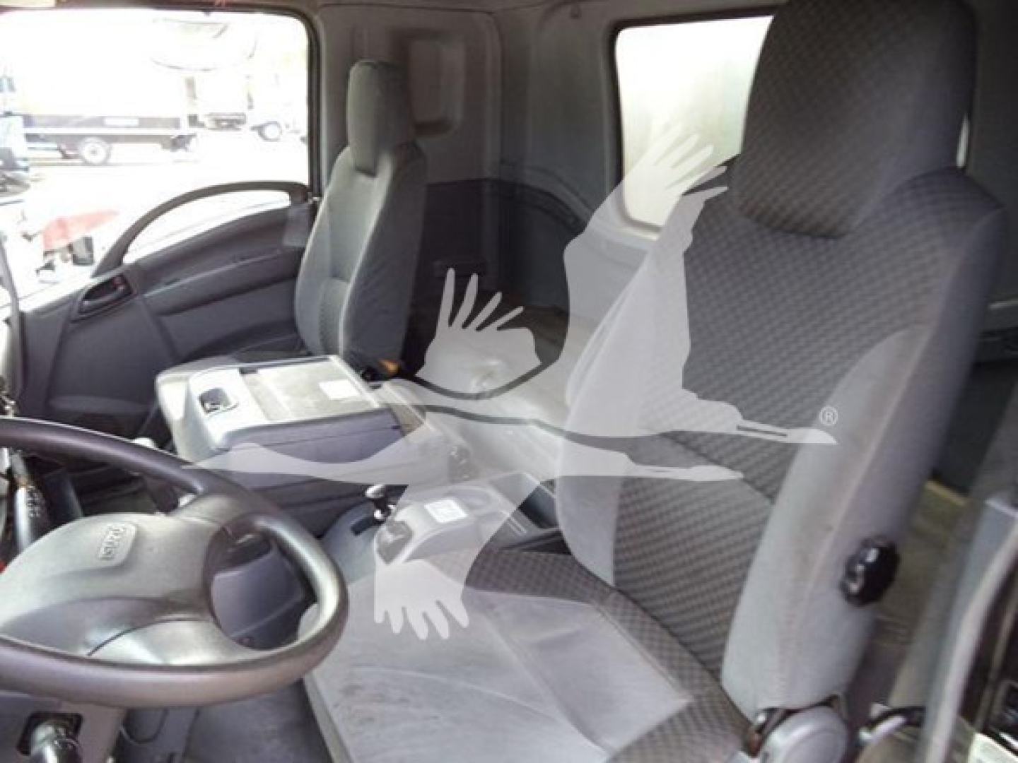 Isuzu truck cabin interior showing driver seat and front passenger seat with steering wheel and center console visible.