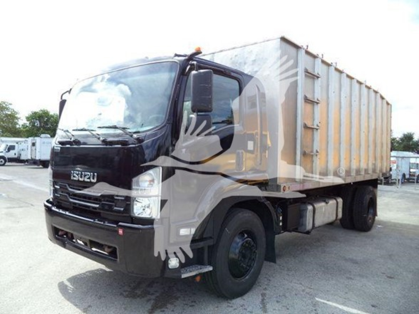 Isuzu dump truck in yard showing front and side view with cargo bed.