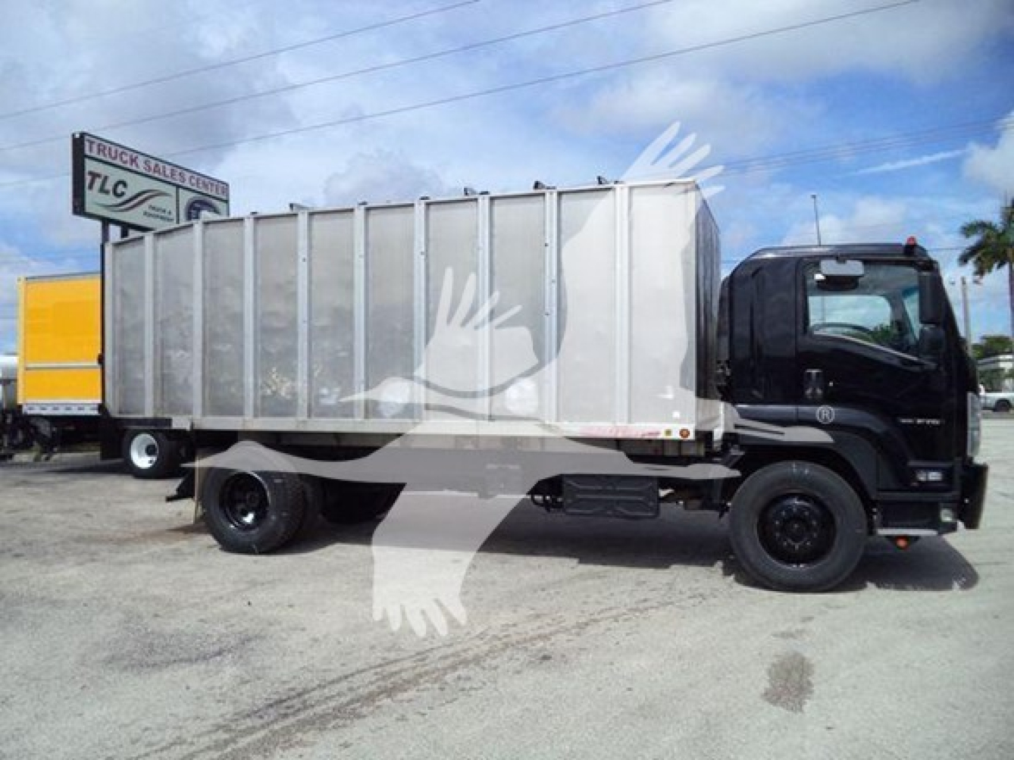 Isuzu FTR truck with large silver dump bed in truck yard