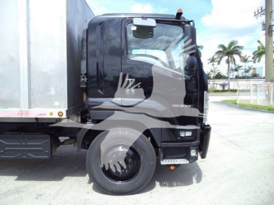 Isuzu truck cab and front wheel showing graffiti-like graphic and part of a chipper truck.