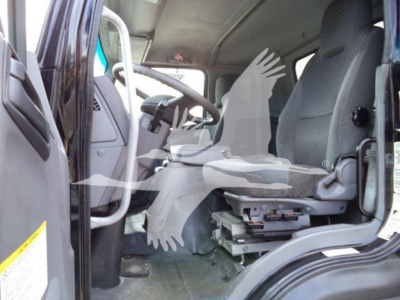 Isuzu truck cab interior showing driver seat and dashboard with pedals and steering wheel.