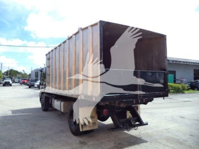Isuzu FTR dump truck in rear three-quarter view showing cargo bed and chassis with trailer hitch, used condition.