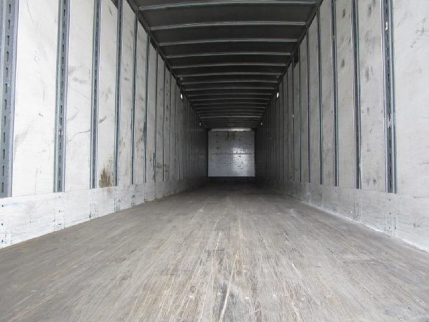 Van trailer cargo interior view showing empty wooden floor and metal sidewalls with ribbed ceiling in a Stoughton van.