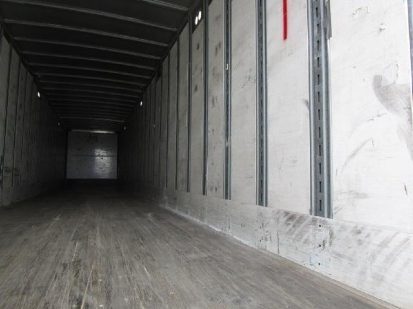 Interior view of a 2014 Stoughton van trailer with wooden floor and metal sidewalls. Dim, empty cargo area showing load rails and rear door opening.