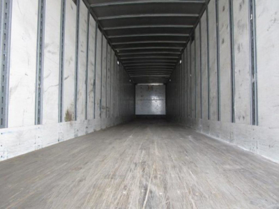 Van trailer cargo interior view showing empty wooden floor and metal sidewalls with ribbed ceiling in a Stoughton van.