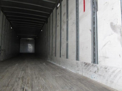 Interior view of a 2014 Stoughton van trailer with wooden floor and metal sidewalls. Dim, empty cargo area showing load rails and rear door opening.