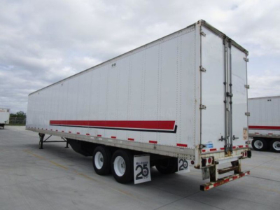 Trailer wagon showing a white Stoughton van trailer with red stripe undercarriage and triple axles in a parking lot.