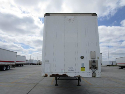 Rear view of a white Stoughton van trailer showing standard rear doors and a tongue jack, with rust at lower edge and a utility box mounted on right side.