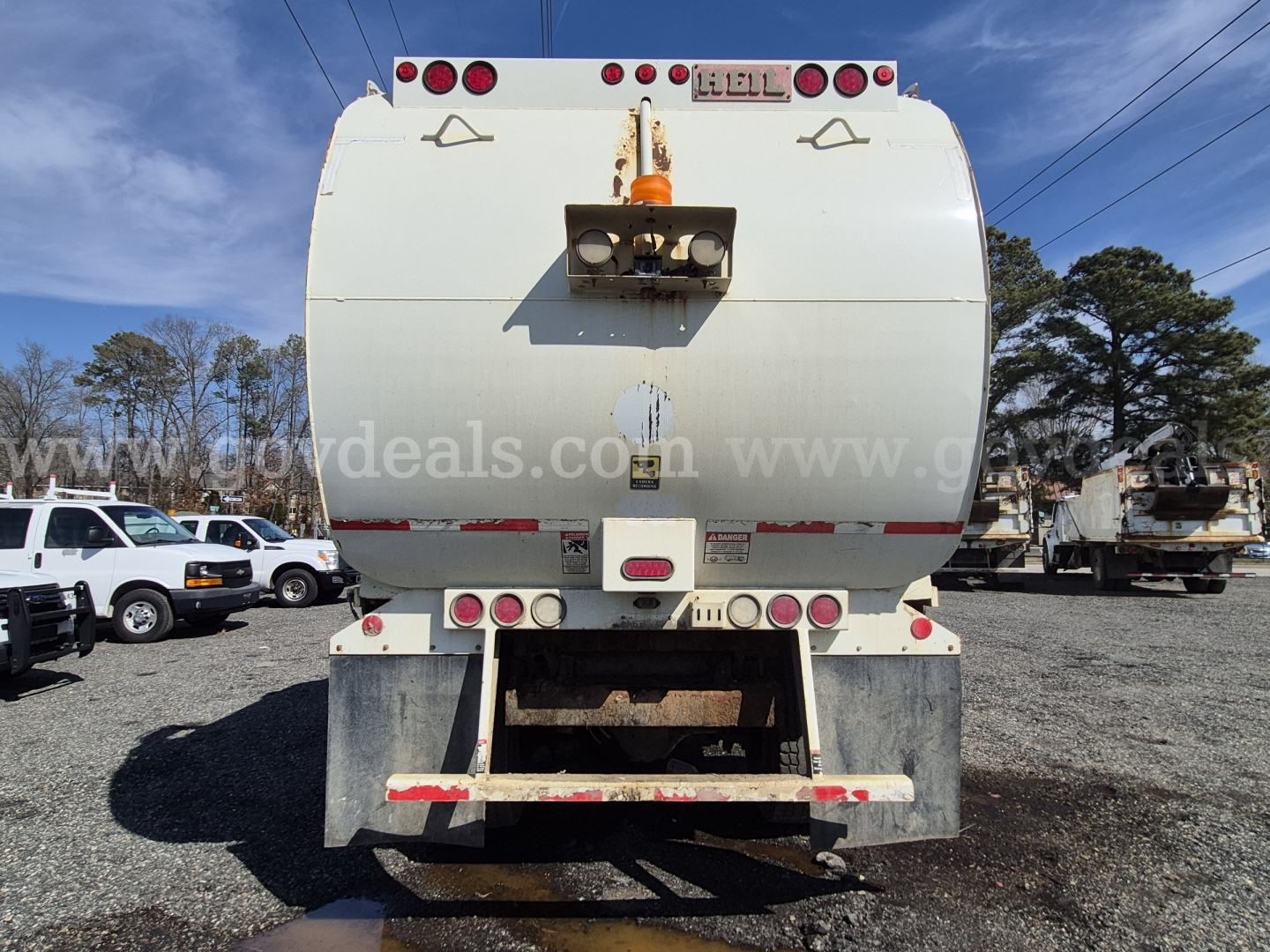 Back view of a white 2017 International 7400 dump truck with rear hydraulic hopper, taillights, and bumper.