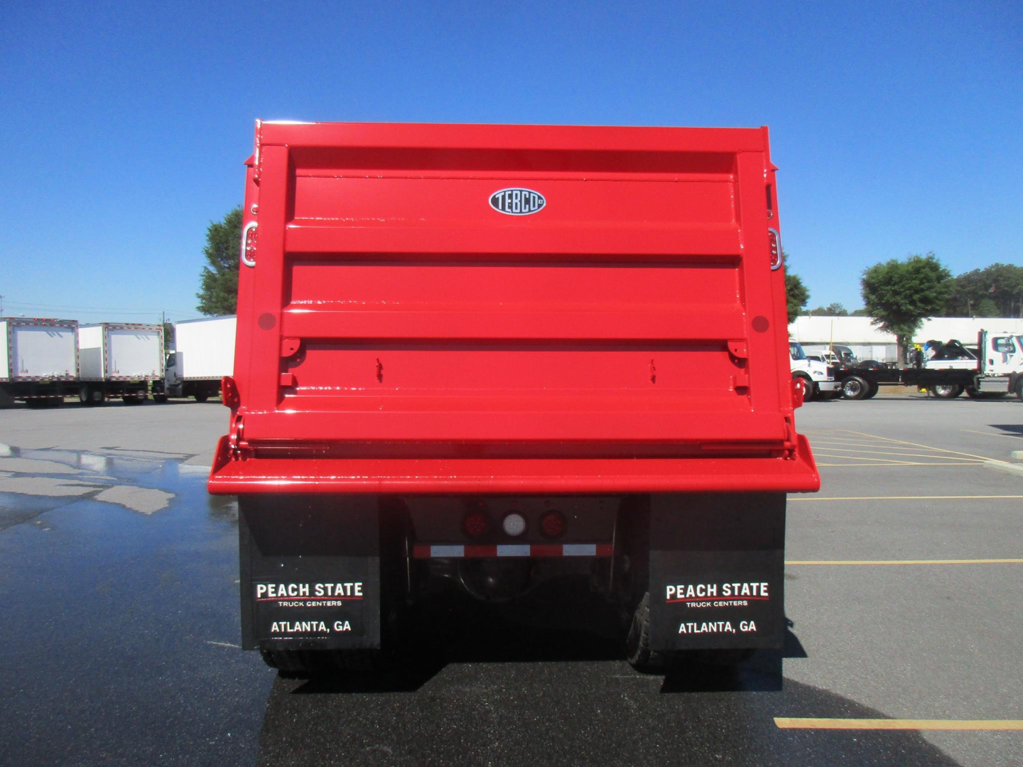 Back of red dump truck bed with TEIBCO logo and black mudflaps showing Peach State Atlanta GA text.